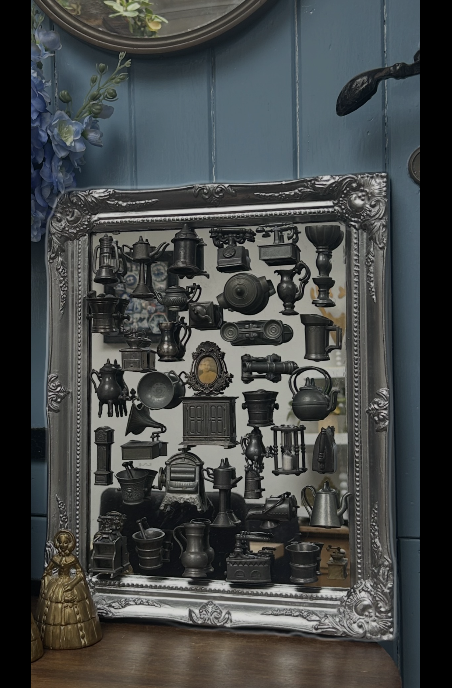 Decoratieve, ingelijste presentatie van zwarte vintage miniaturen tegen een blauwe muur.