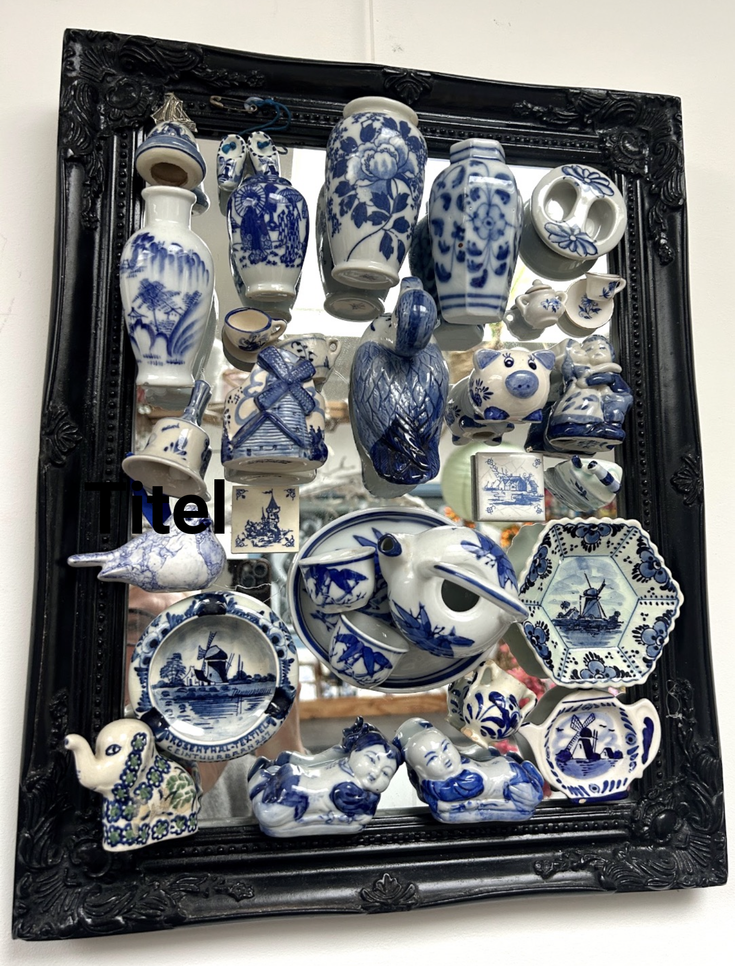 Blauw-witte porseleinen miniaturen tentoongesteld in een vitrinekast met zwarte lijst.
