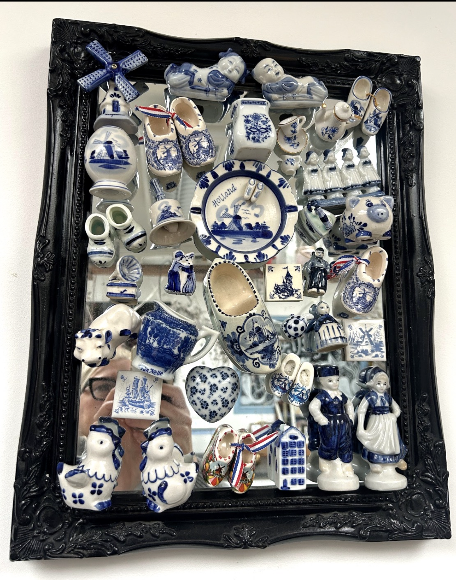 Blauw-witte Delftsblauwe keramische beeldjes en schalen, tentoongesteld in een ingelijste vitrine.