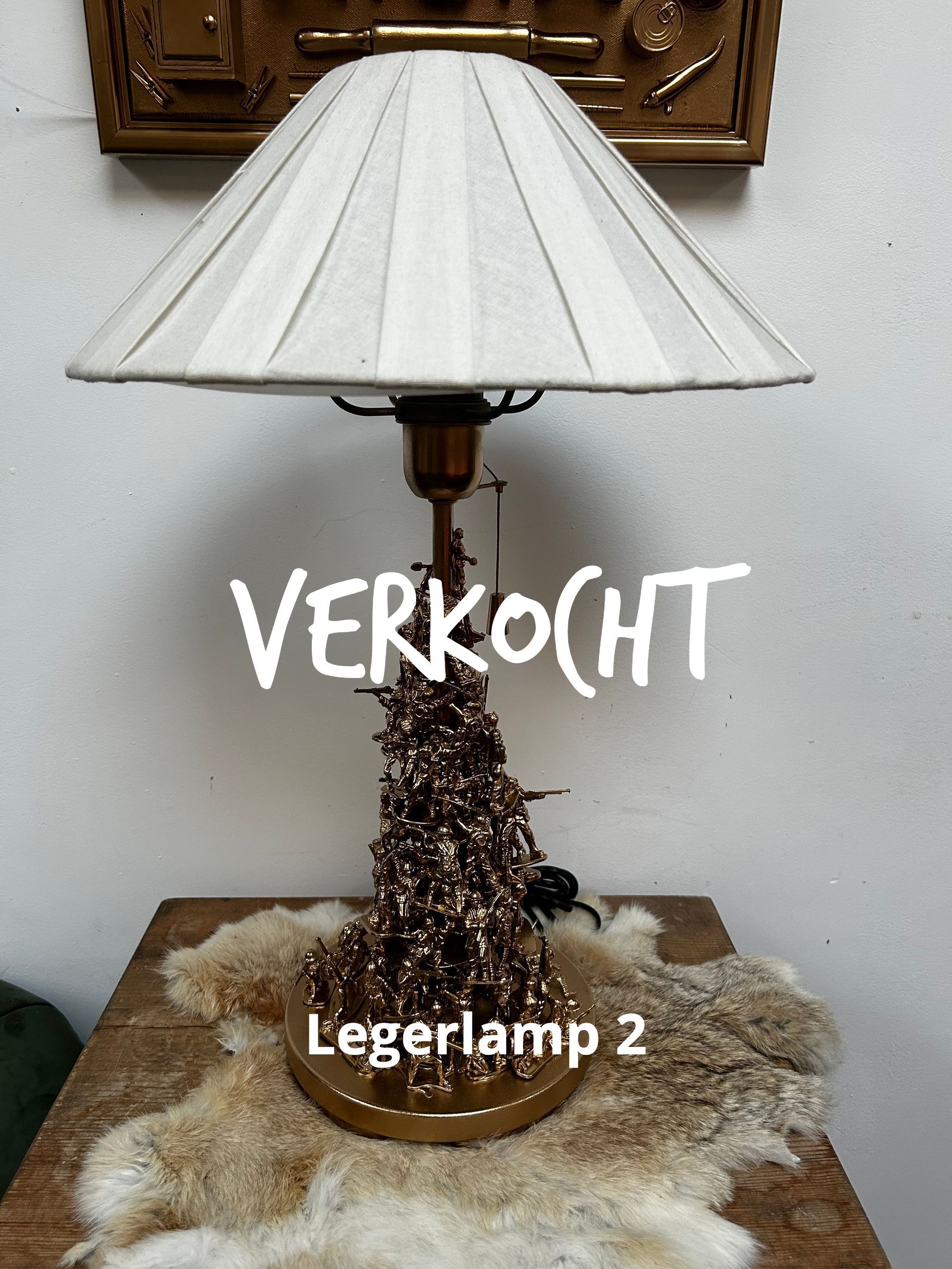 Tafellamp met witte geplooide kap en bruine kralenvoet op een decoratief doek, gemerkt met 