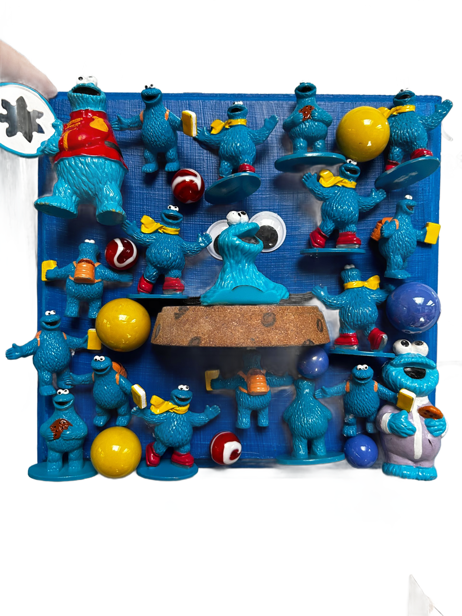Blauwe speelmat met speelgoedfiguurtjes, ballen en een bruin platform, gerangschikt in een kleurrijke, rommelige scène.