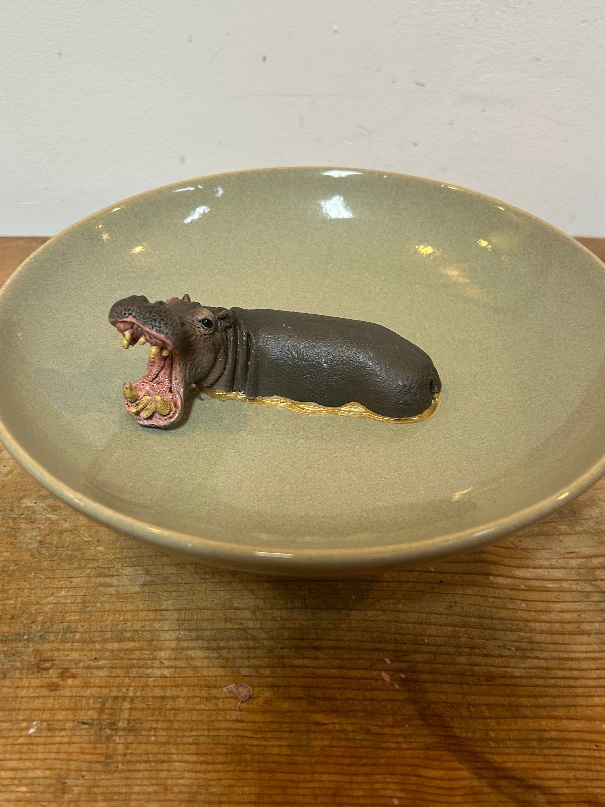 Een klein, donker, slakachtig wezentje op een beige bord op een houten tafel.