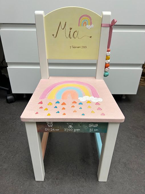 Roze kinderstoel met regenboog en sterren, versierd met de naam ‘Pia’ op de rugleuning