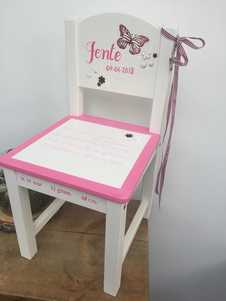 Wit bureau voor een kind, met roze randjes en een vlindersticker met naam, versierd met een strik op de rugleuning.