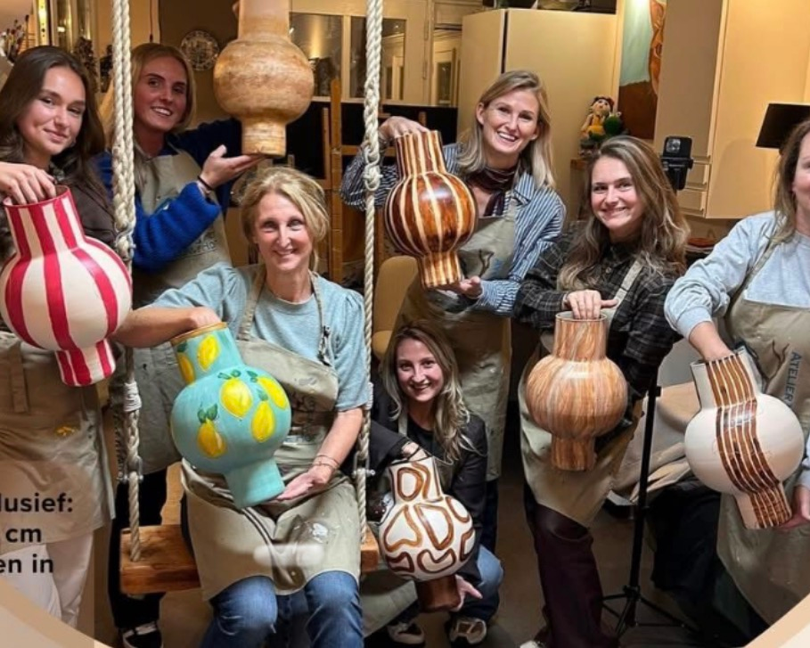 Zes vrouwen poseren binnen met grote, gestreepte en van patronen voorziene decoratieve kalebassen.