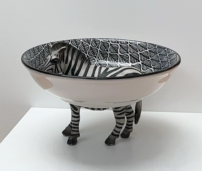 Zebravormige kom met zwart-witte strepen en vier zebrapoten op een witte achtergrond.