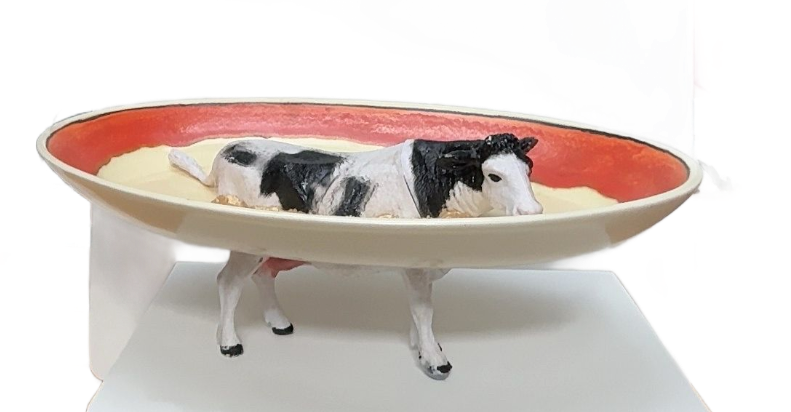 Een koe staat in een gigantische witte kom met rode vloeistof erin.