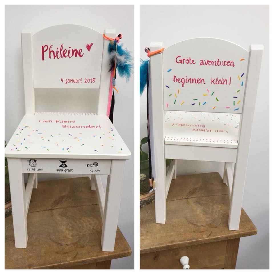Twee witte stoelen met Franse felicitatieteksten en kleurrijke versieringen op een betegelde vloer