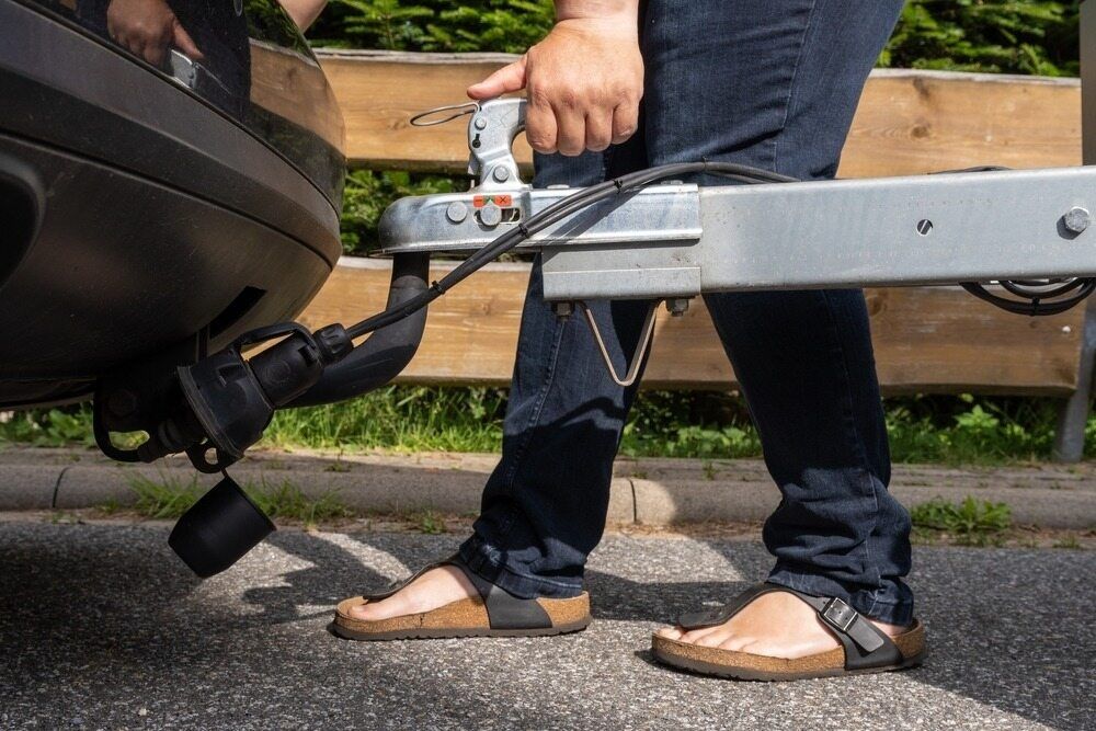 A Person is Attaching a Trailer to the Back of a Car — Johnson River Towing In Innisfail, QLD
