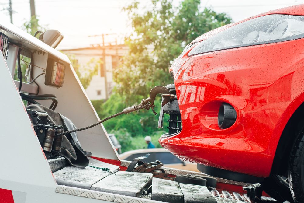 A Red Car is Being Towed by a Tow Truck — Johnson River Towing In Innisfail, QLD