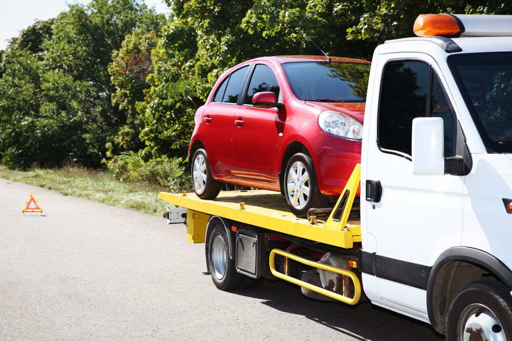 A Red Car is Being Towed by a Tow Truck — Johnson River Towing In Innisfail, QLD