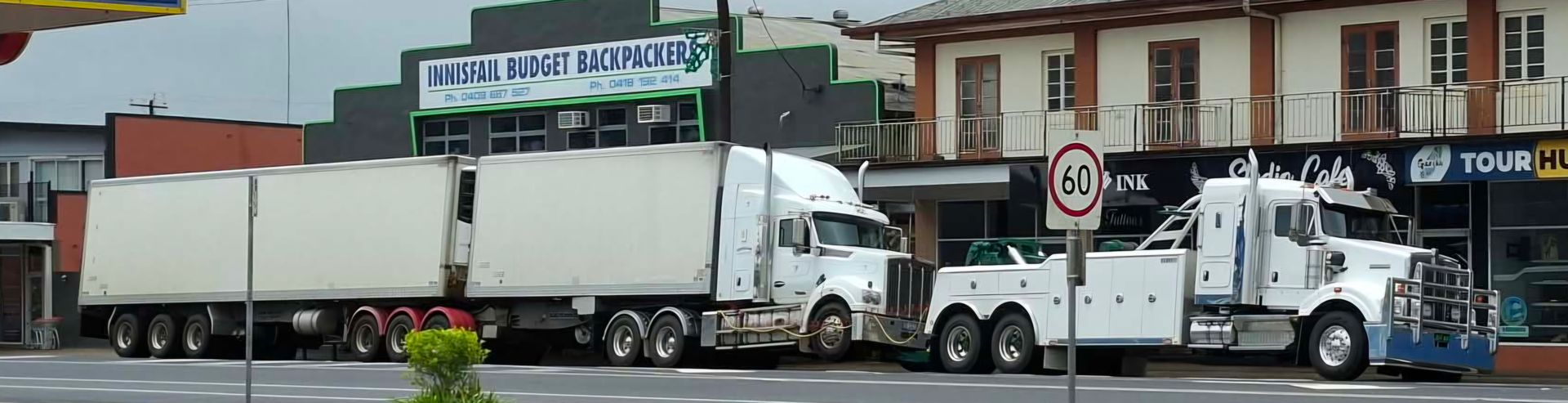 A Semi Truck is Driving Down a Road With Trees in the Background — Johnson River Towing In Innisfail, QLD