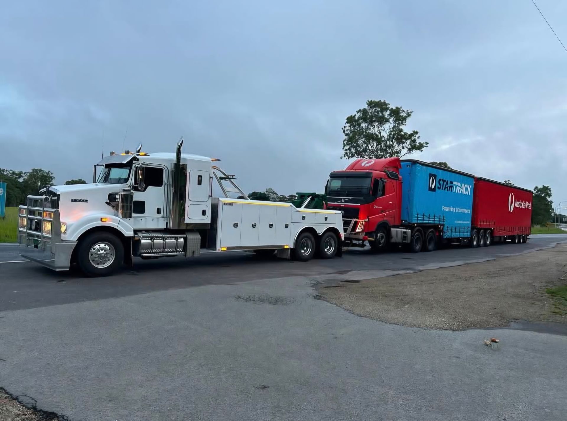 A Tow Truck is Towing a Damaged Car on the Side of the Road — Johnson River Towing In Innisfail, QLD