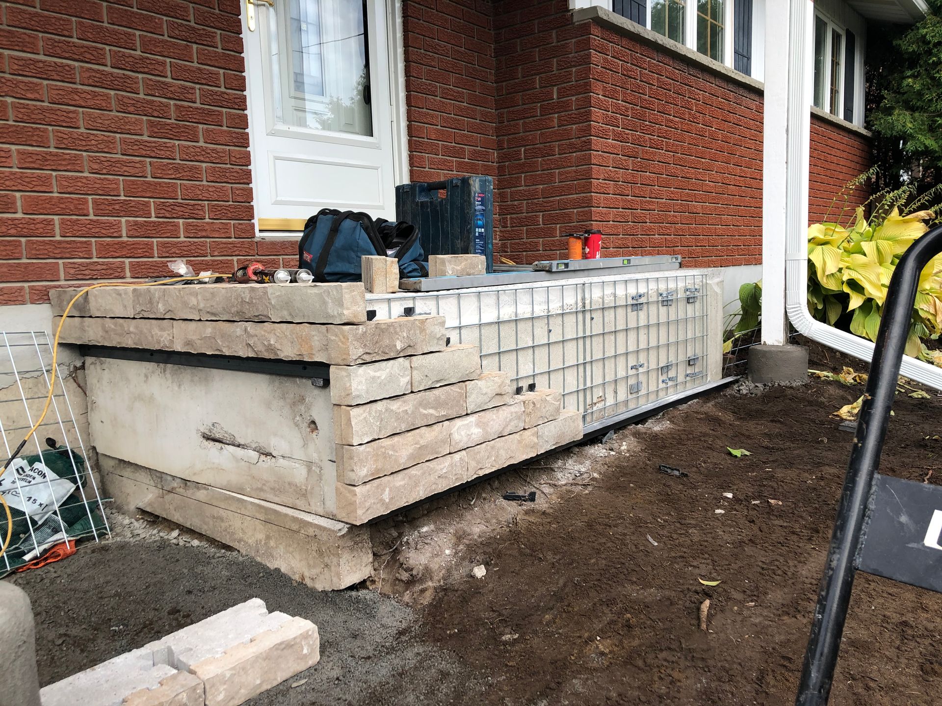 Une maison en briques avec un escalier en béton en construction devant elle.