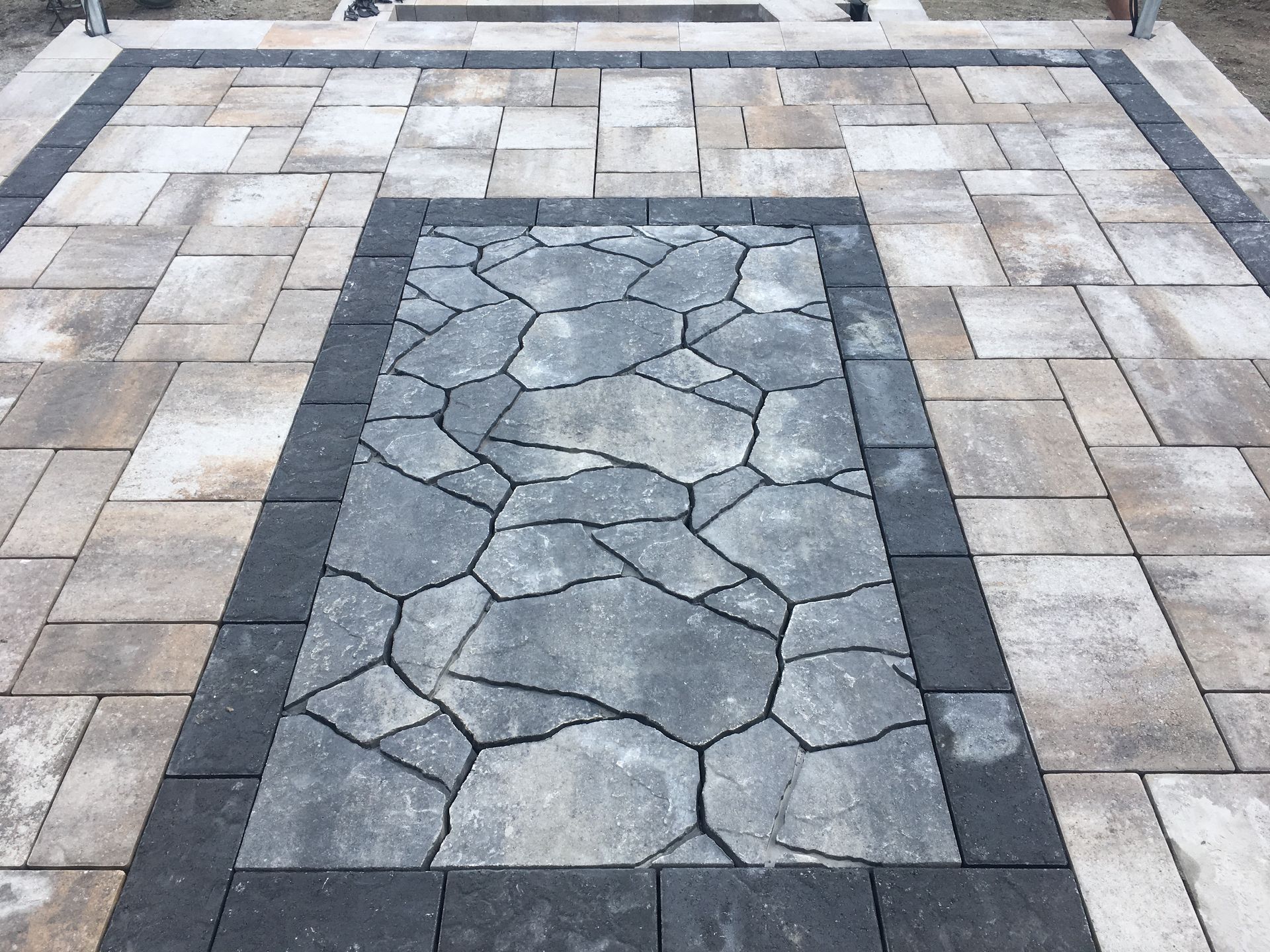 Un patio avec une bordure en pierre et une allée en briques
