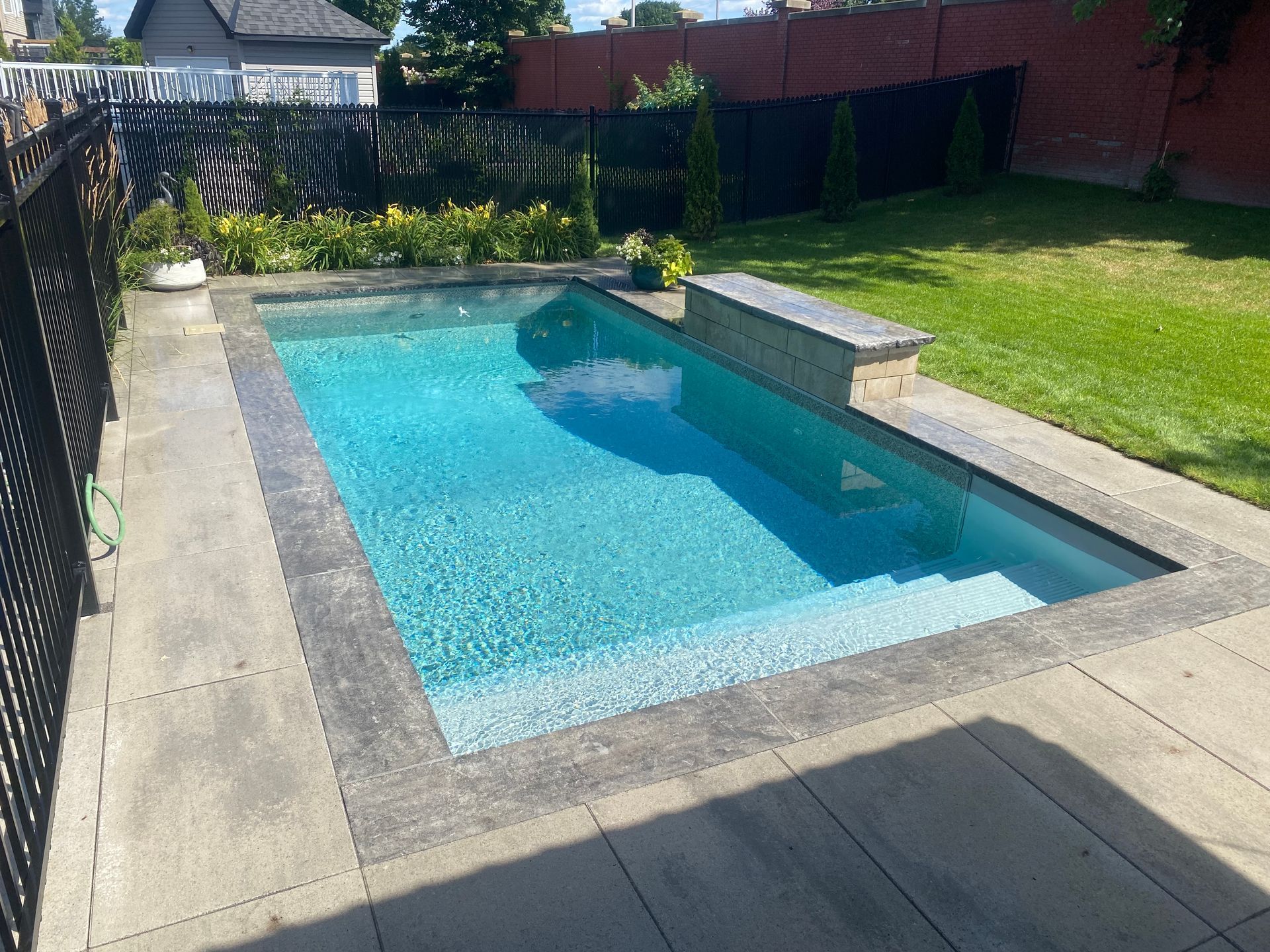 A large swimming pool is surrounded by a fence in a backyard.
