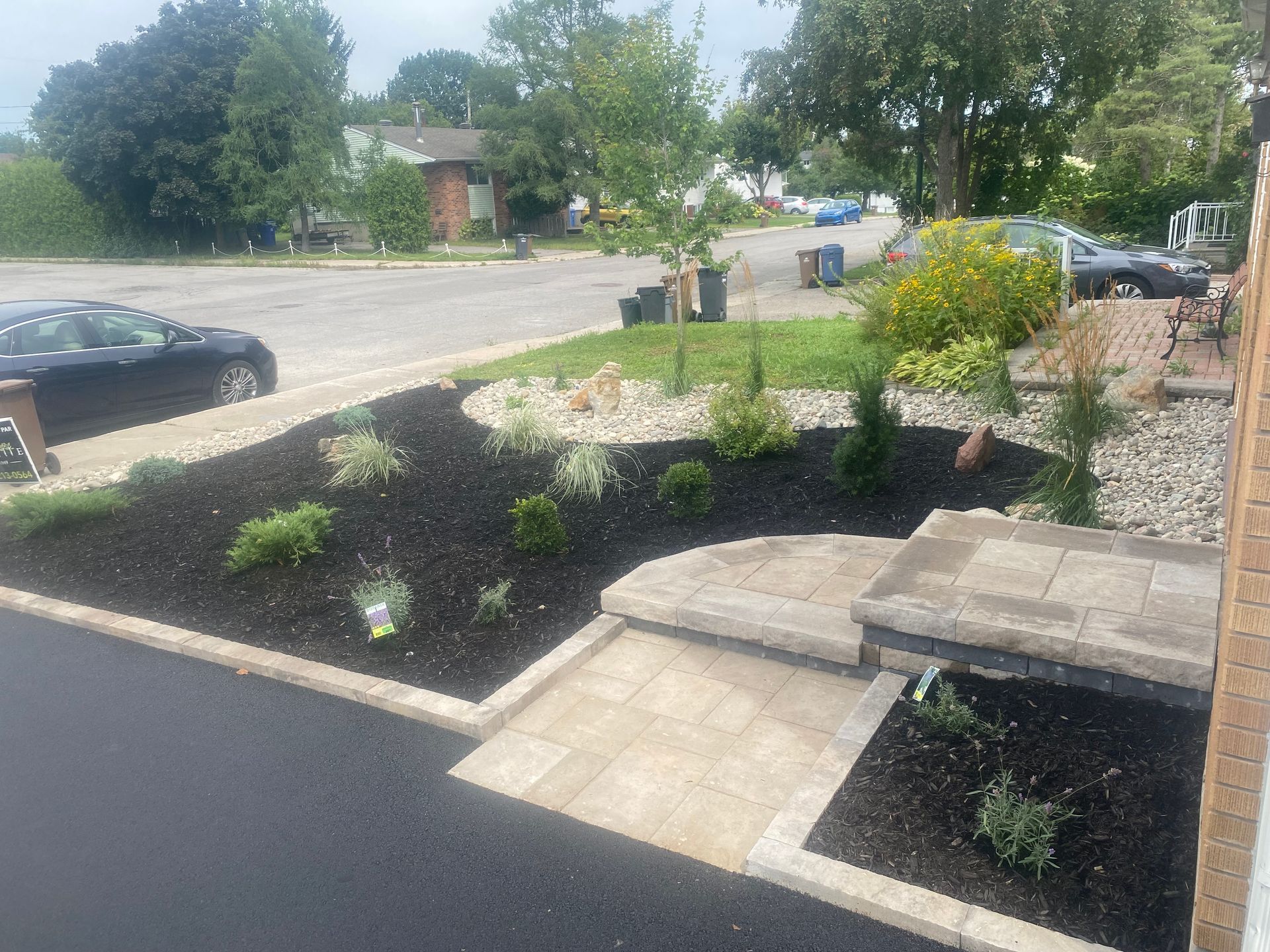 Une voiture est garée dans l'allée d'une maison à côté d'un jardin.