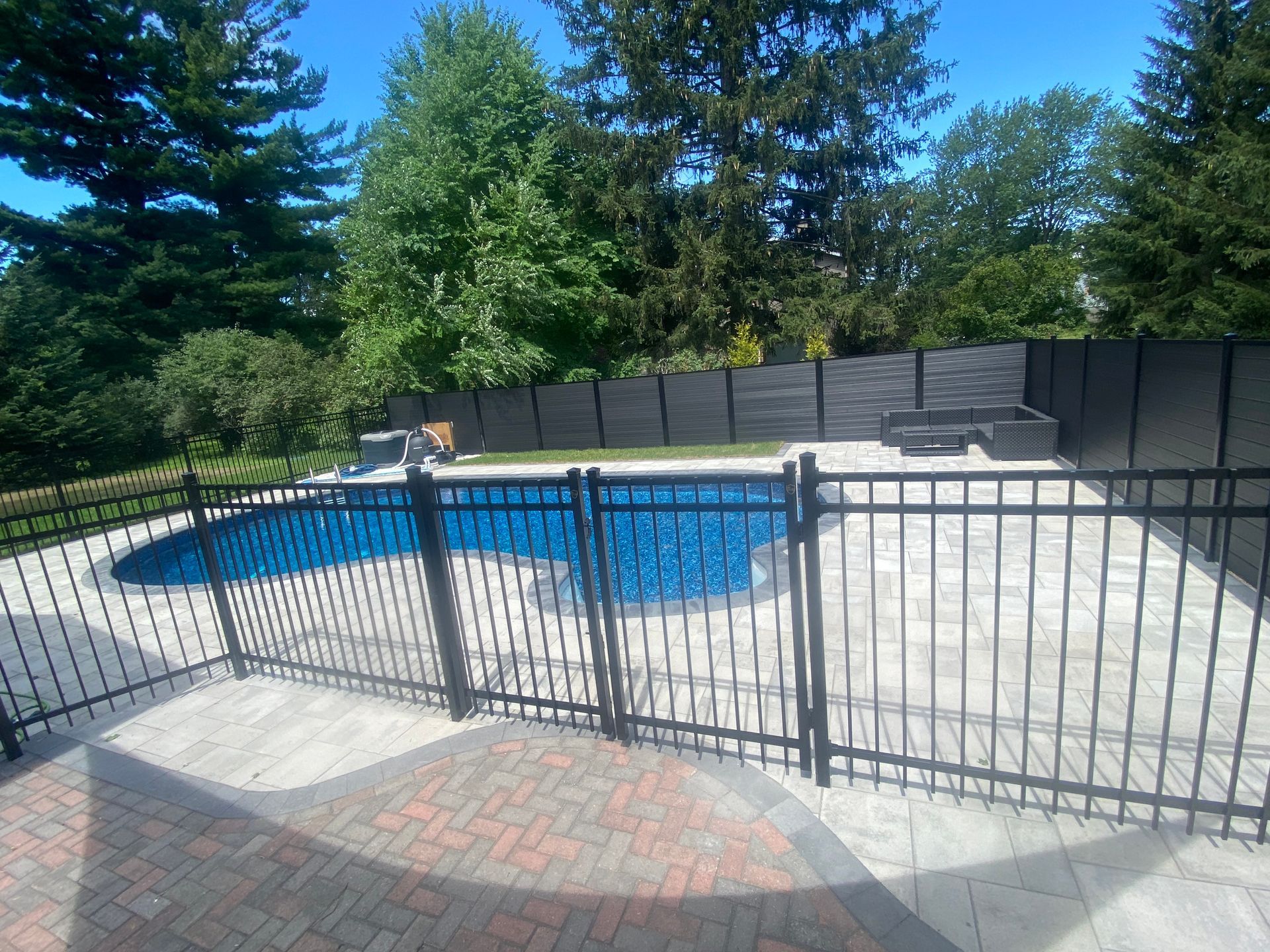 A black fence surrounds a large swimming pool