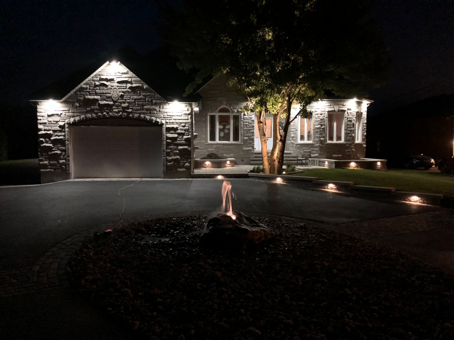 Une maison est éclairée la nuit avec un foyer devant elle.