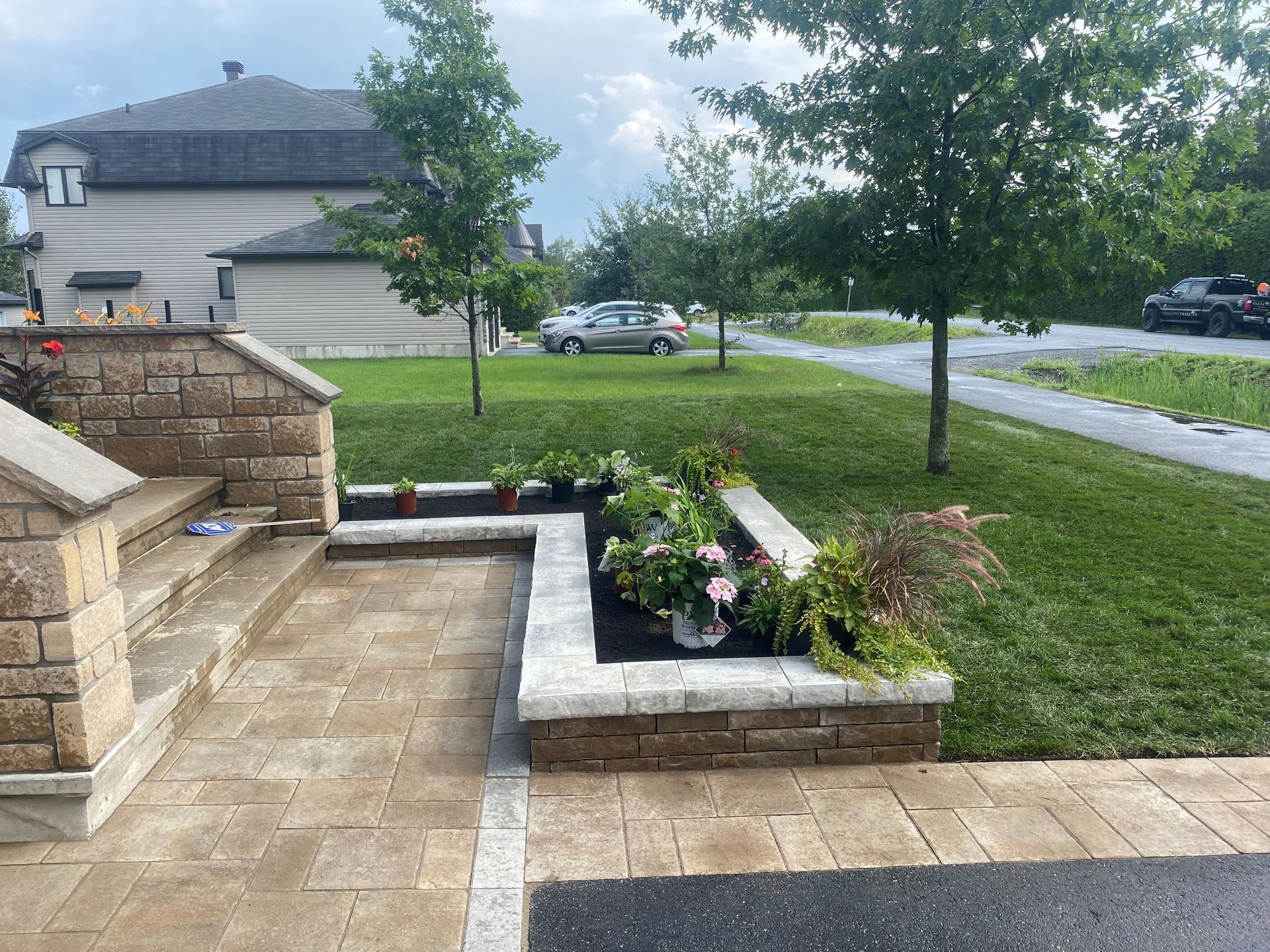 Une allée en briques menant à une maison avec une jardinière remplie de fleurs.