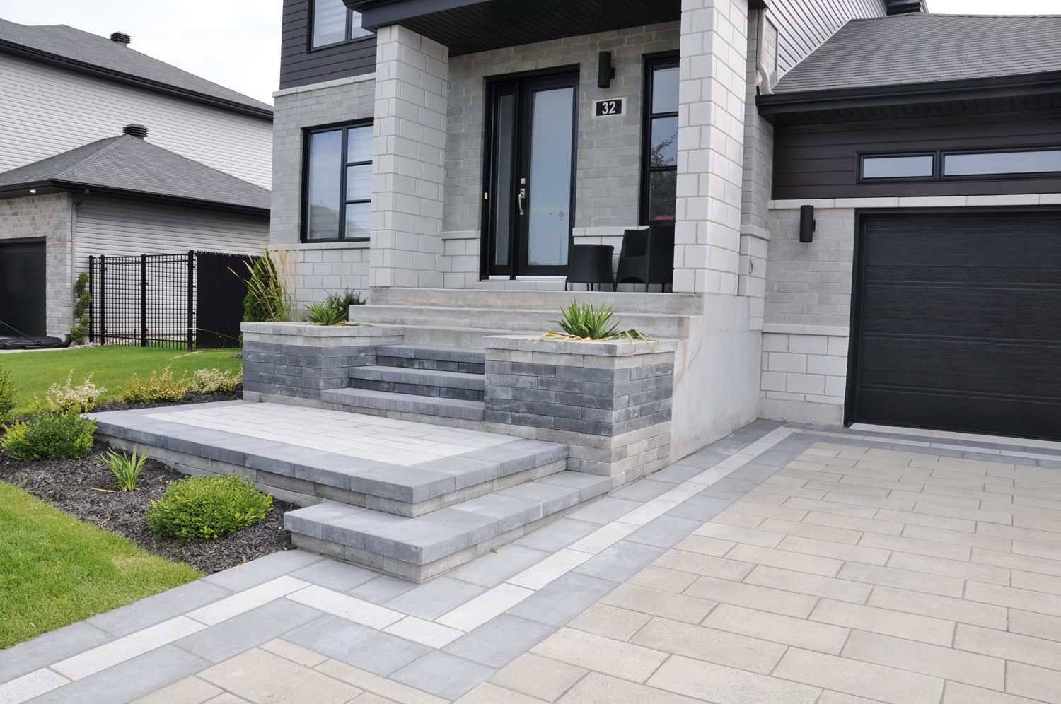 La façade d'une maison avec des escaliers menant à la porte d'entrée et une porte de garage noire.