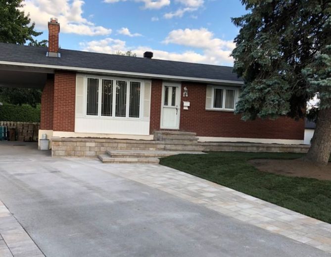 Une maison en briques avec une allée en béton devant