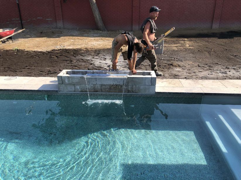 Deux hommes travaillent sur une cascade dans une piscine.