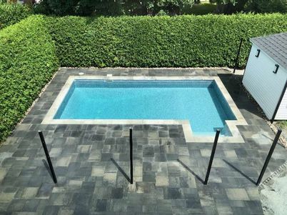 Une petite piscine dans une cour arrière avec un hangar en arrière-plan