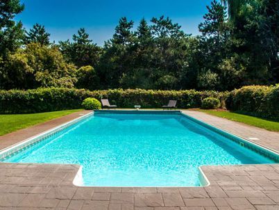 Une grande piscine entourée d'arbres et d'arbustes par une journée ensoleillée
