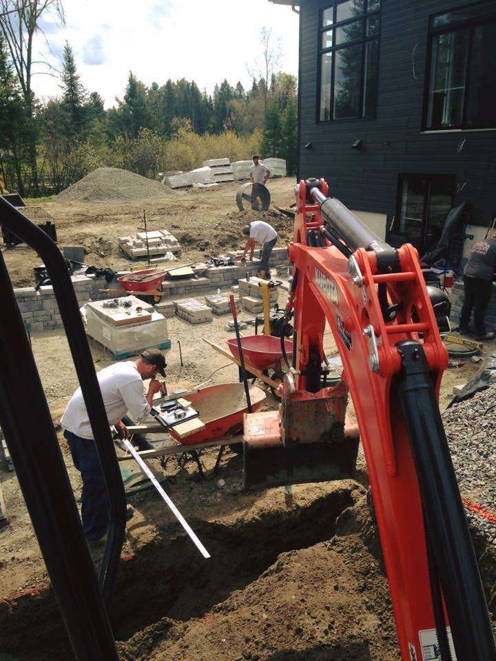 Une grande excavatrice rouge est utilisée pour creuser un trou dans le sol
