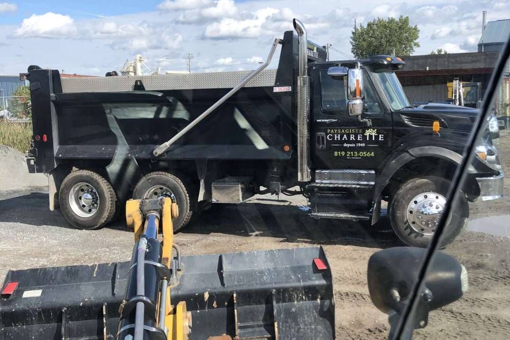 Un camion à benne basculante est garé sur un terrain en terre à côté d'un bulldozer.