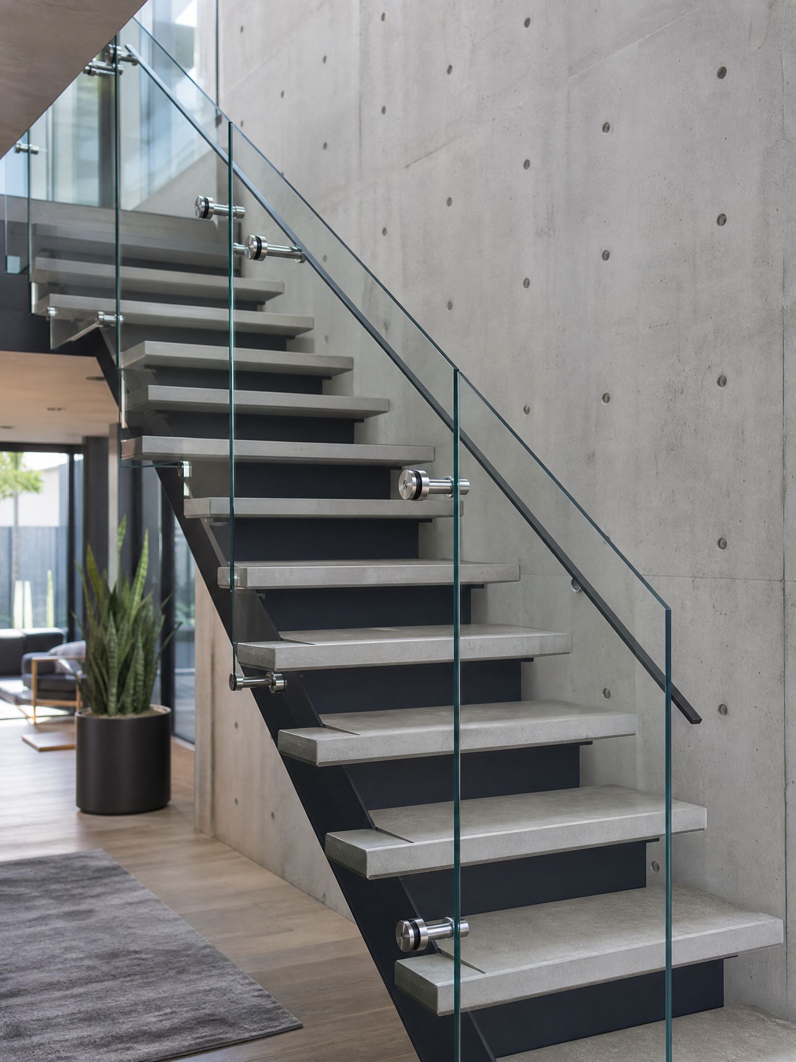 Modern indoor staircase with glass railing and concrete wall in a loft-style space
