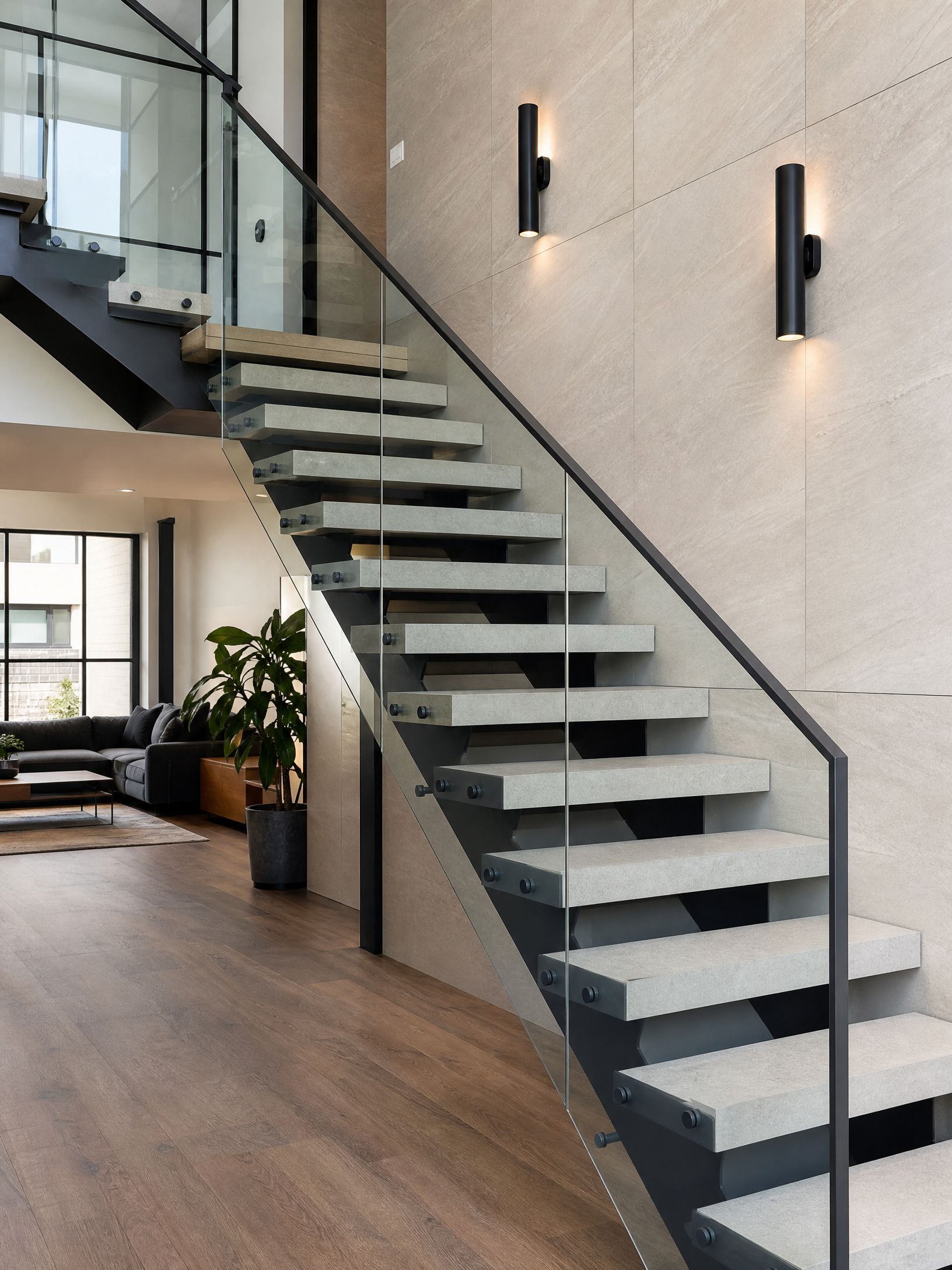 Modern indoor staircase with black railings, floating steps, and wall sconces in a bright loft interior