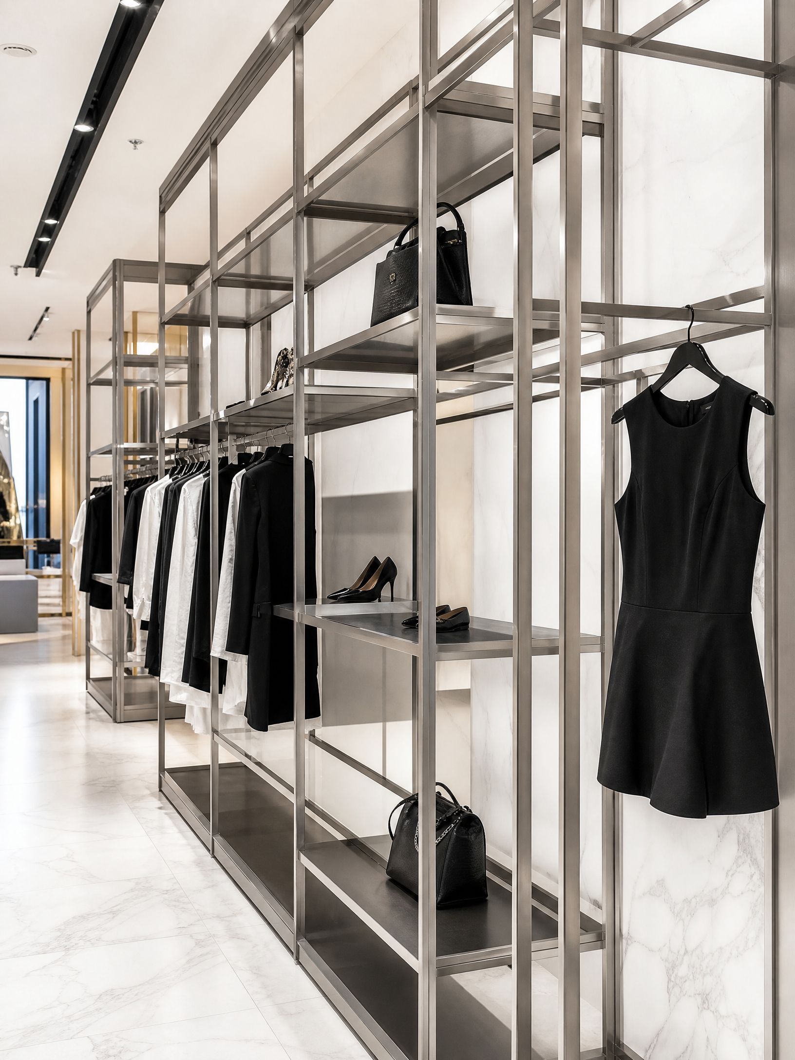 Modern clothing store interior with metal racks, hanging black dresses, and shoes on shelves