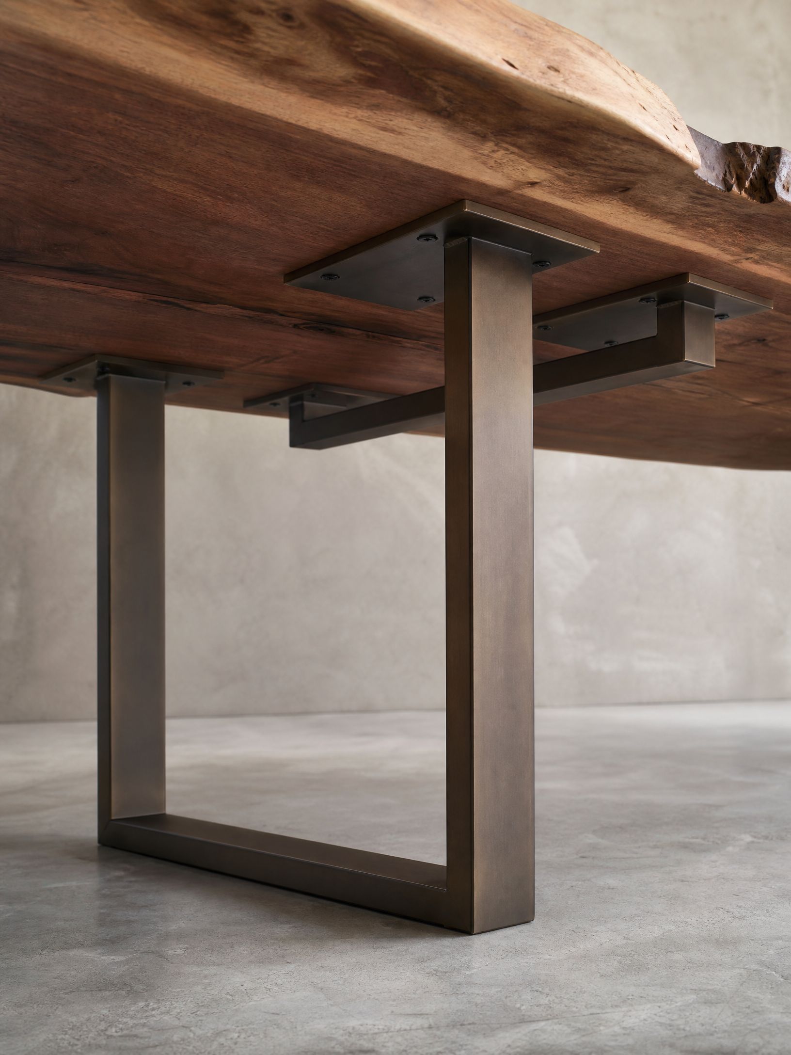 Live-edge wooden table with a dark metal base on a concrete floor.