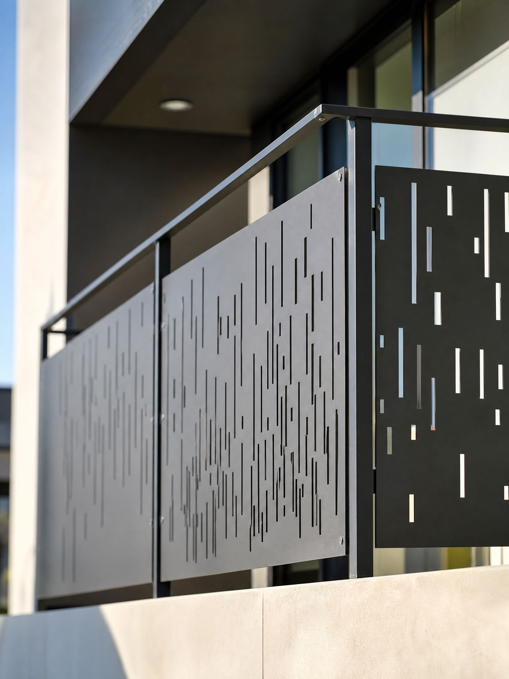 Modern balcony with dark perforated metal railing and concrete wall under a building overhang