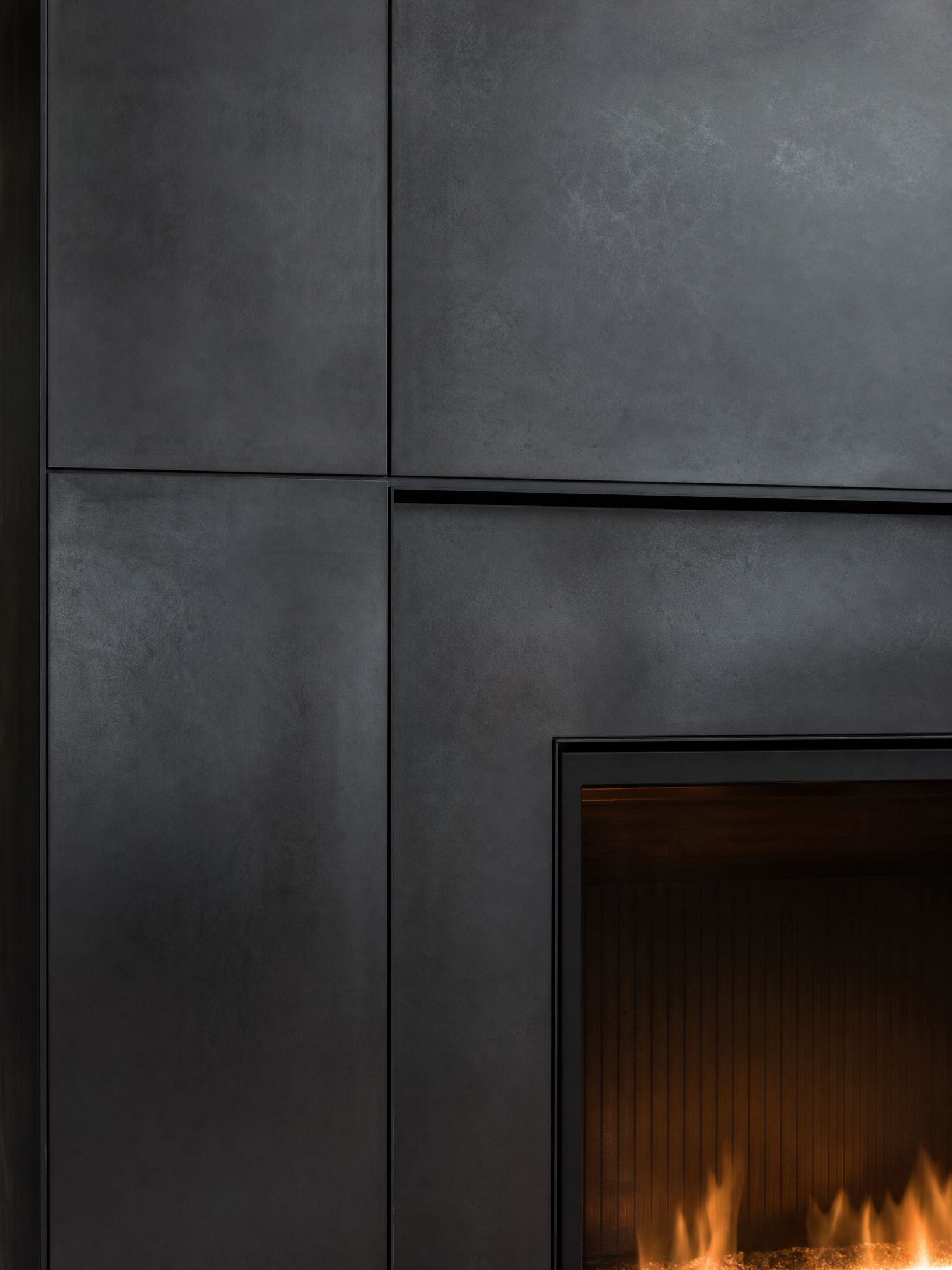 Dark gray tiled fireplace wall with a small fire burning in the hearth