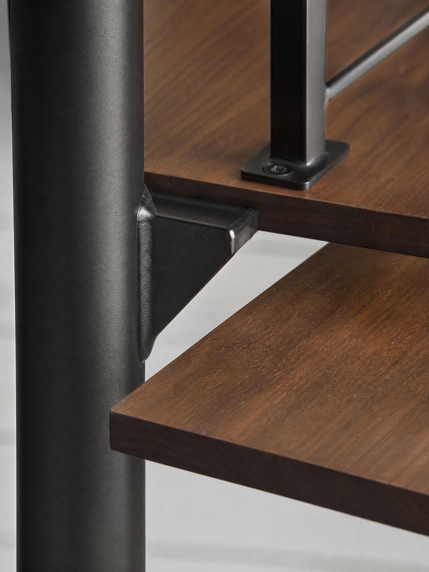 Close-up of black metal table legs and dark wood shelves in a modern furniture frame.