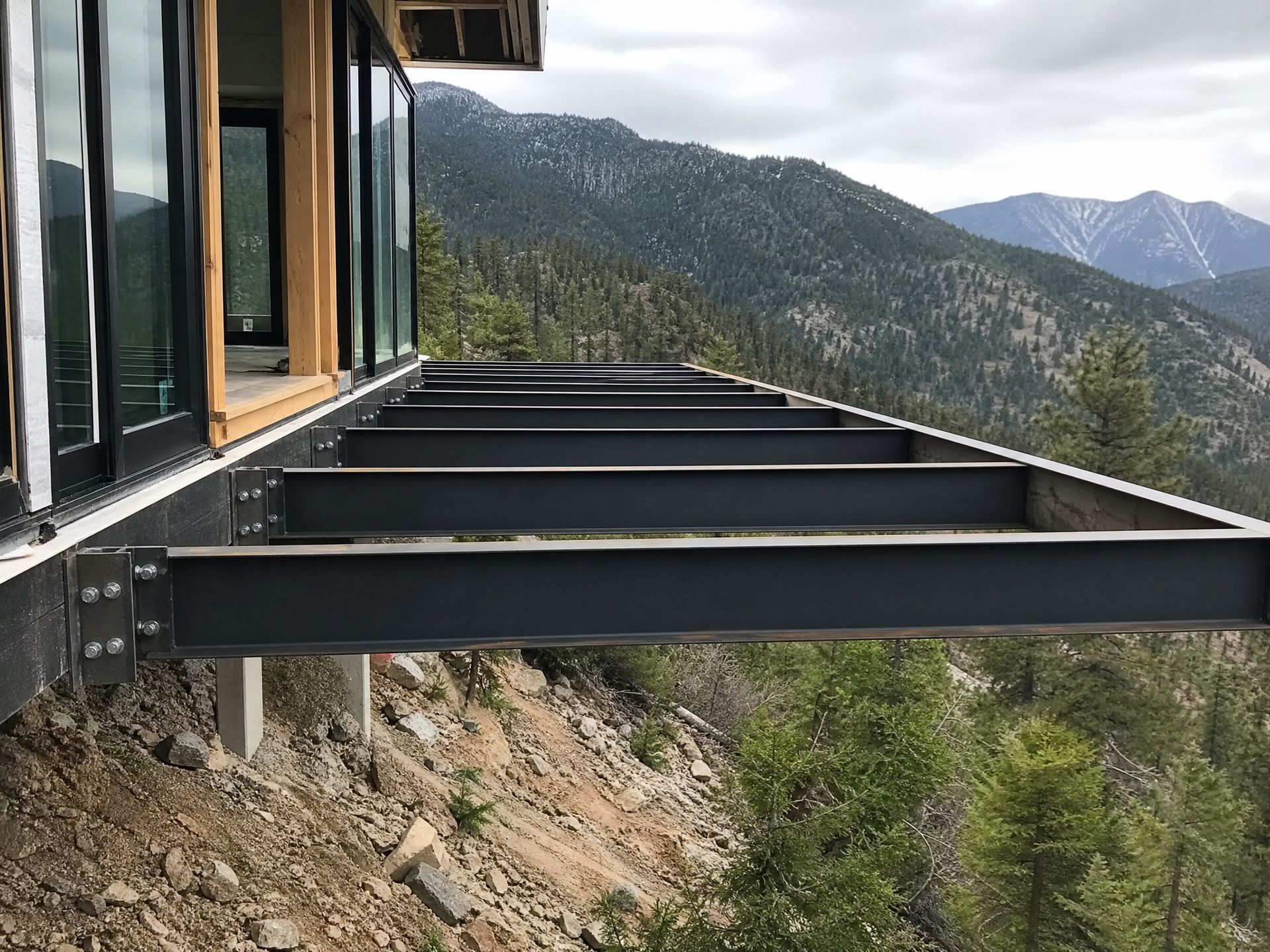 Modern house deck with steel beams overlooking a forested mountain valley