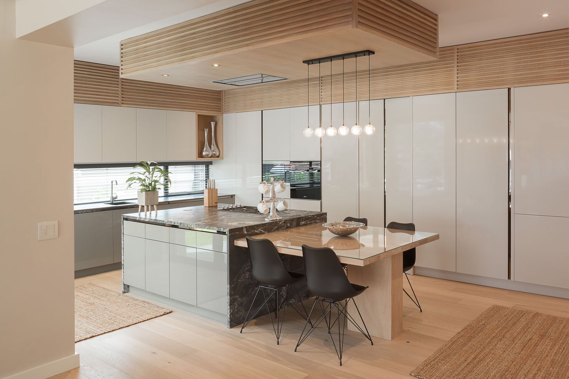 Modern kitchen and dining area with island, pendant lights, wood ceiling, and white cabinets