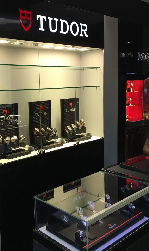 Tudor watch display in a jewelry store, with illuminated cases and black-and-red branding.