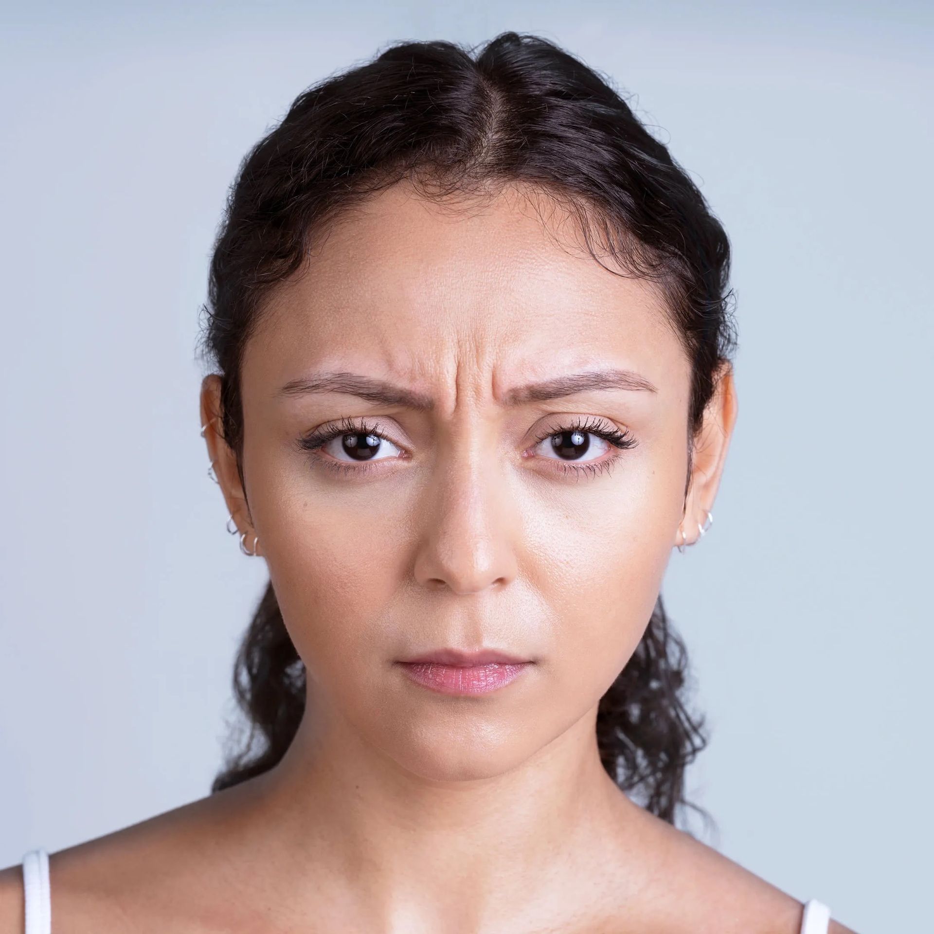 Woman with furrowed brow and pursed lips, looking directly at the viewer.