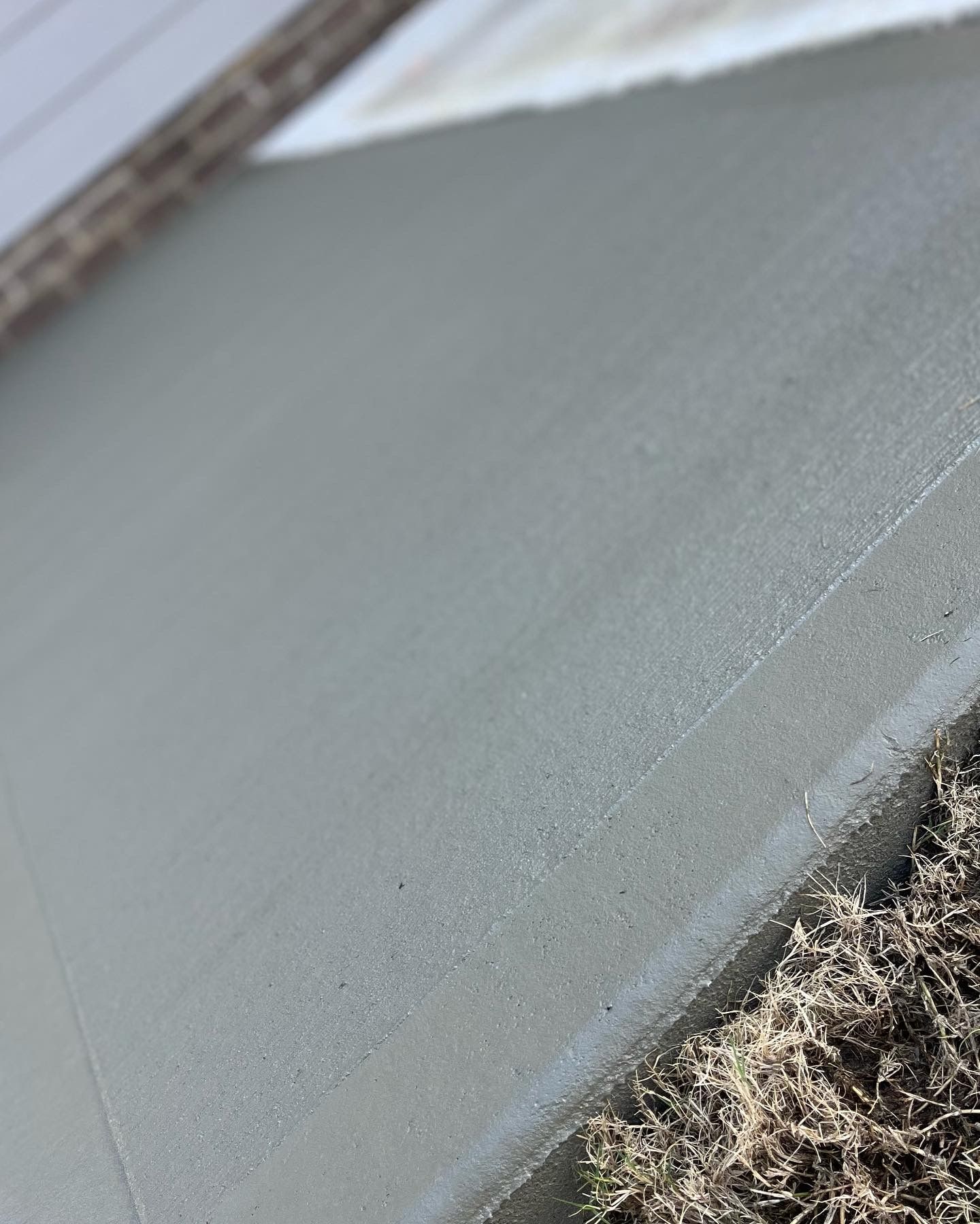 Freshly poured, gray concrete sidewalk with a textured surface