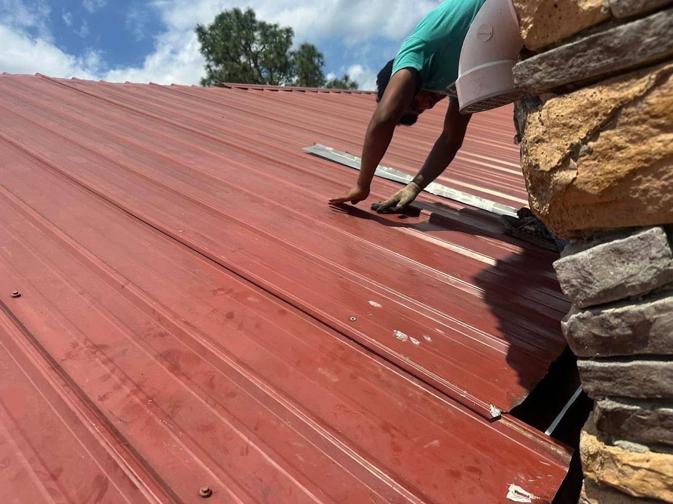 4H Roofing technician installing a red metal roofing system on a residential home in Central Georgia