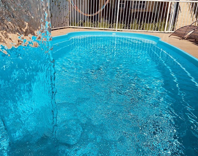 Em um dia ensolarado, uma cascata deságua em uma piscina azul brilhante.