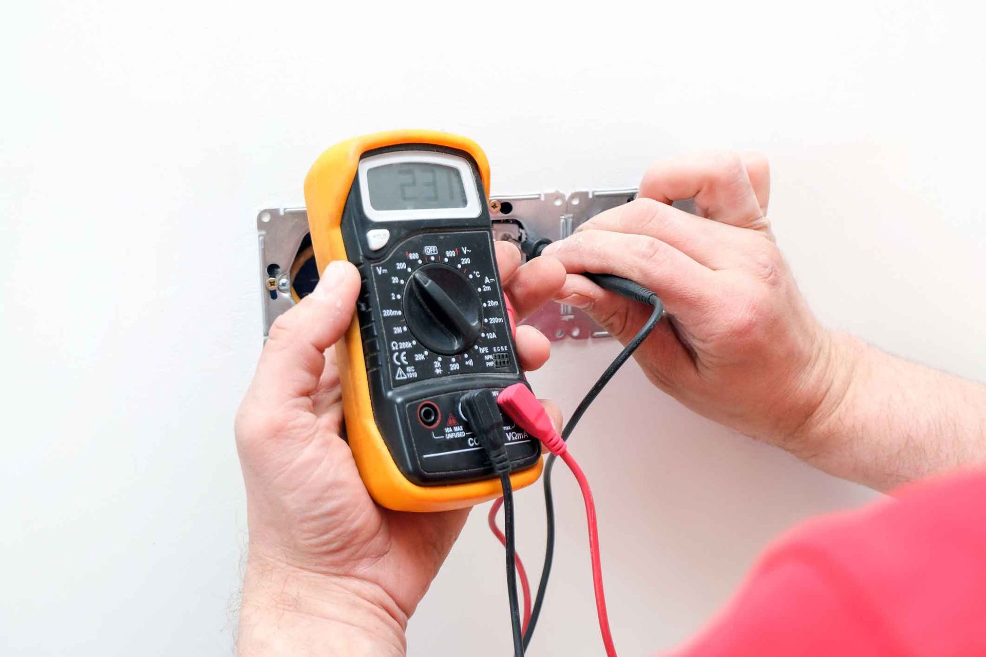 A Man Is Working On A Wall With A Pair Of Pliers - Michael Lozano Electrical Pty Ltd