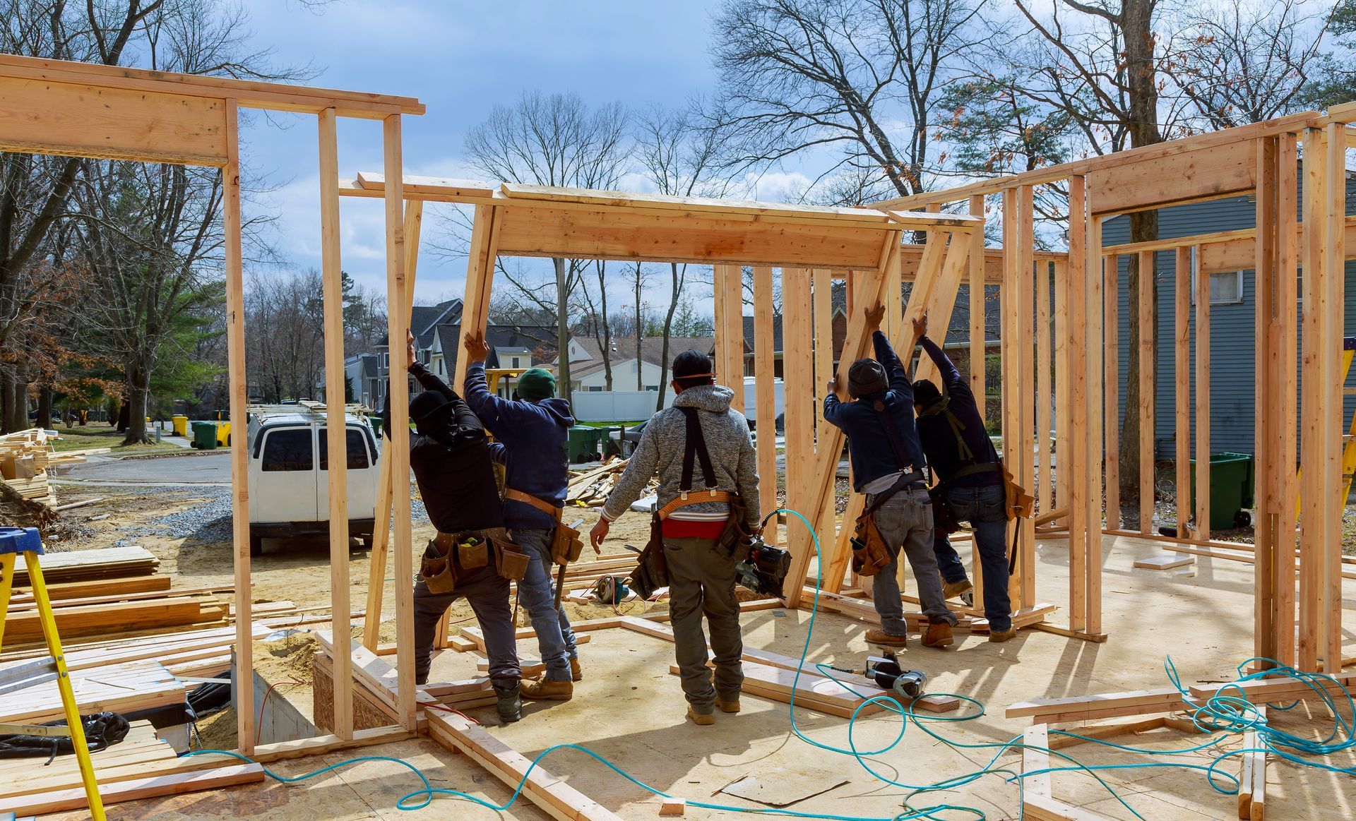 Construction crew framing house walls on a wooden foundation in a sunny outdoor site