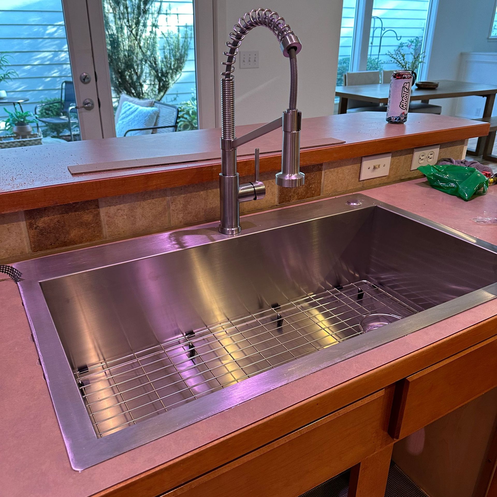 Stainless steel farmhouse sink with tall chrome faucet by a window in a kitchen Stainless steel farmhouse sink with tall chrome faucet by a window in a kitchen