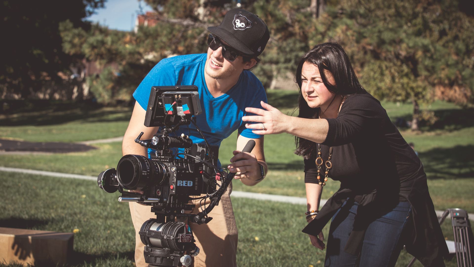 A man and a woman are standing in front of a camera.