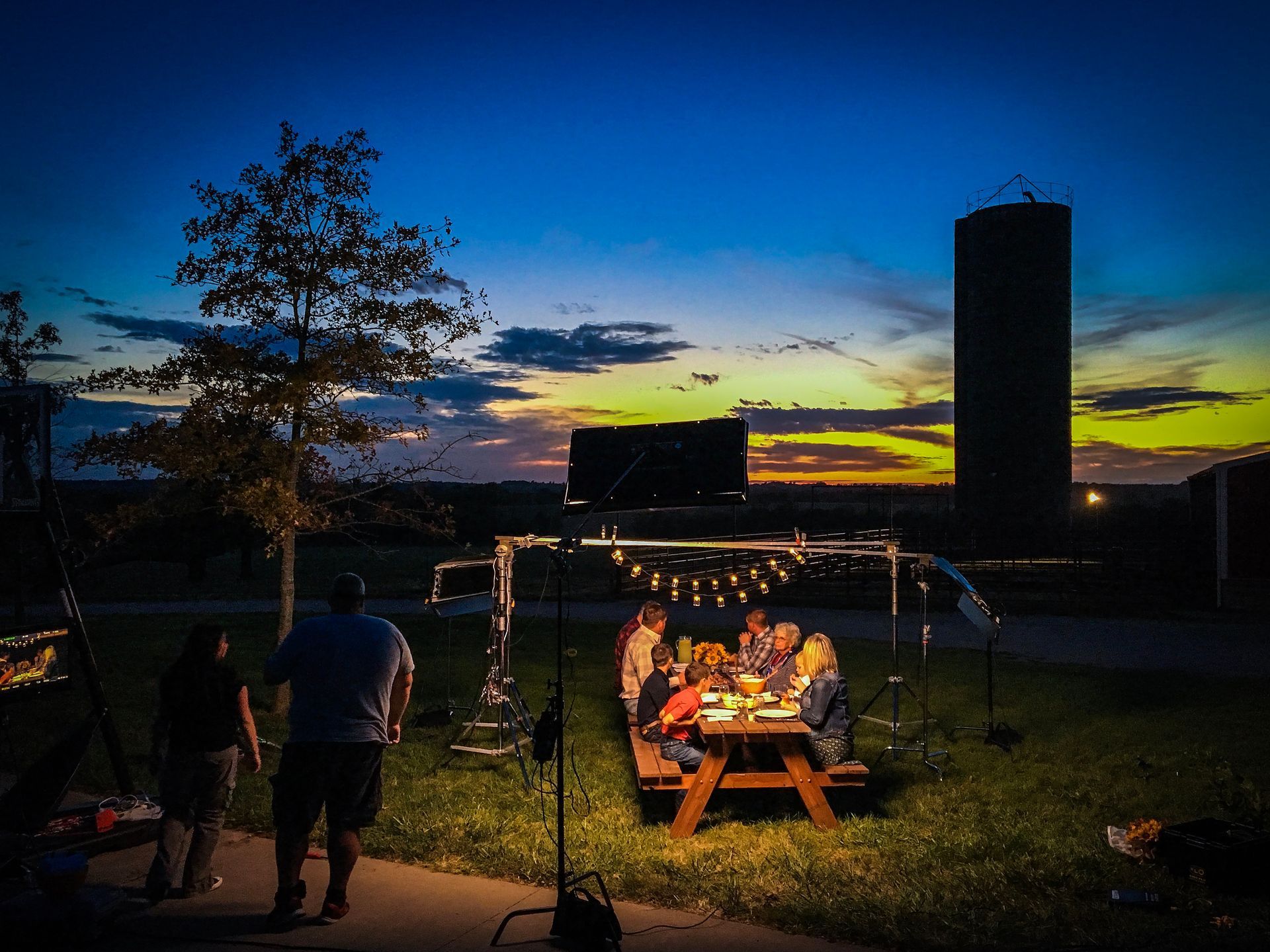 A group of people sitting around a picnic table at night